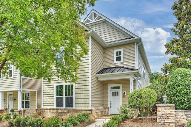 view of front of house featuring a standing seam roof, brick siding, and metal roof