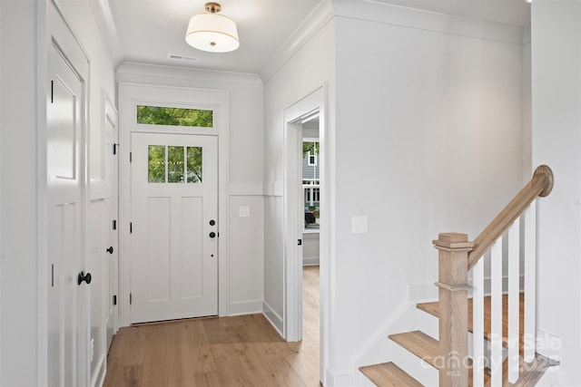 entryway featuring light wood finished floors, baseboards, visible vents, stairs, and crown molding