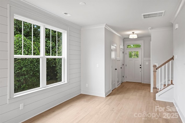 entrance foyer featuring ornamental molding, plenty of natural light, visible vents, and light wood-style floors