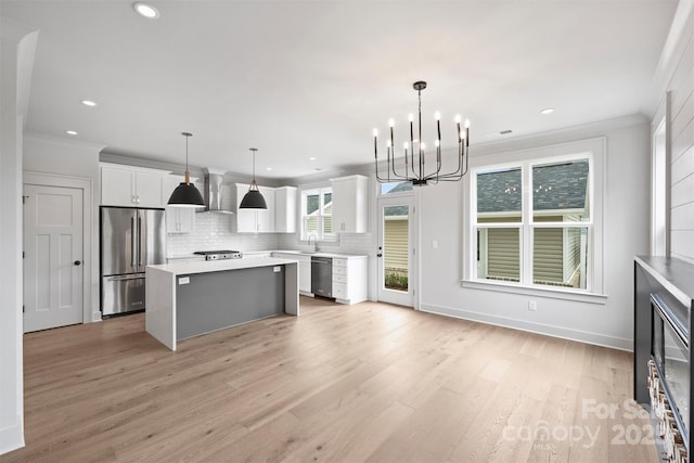 kitchen featuring a kitchen island, white cabinets, light countertops, appliances with stainless steel finishes, and decorative light fixtures