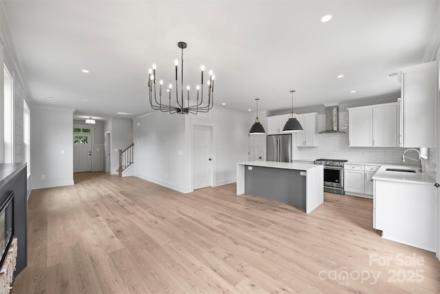 kitchen featuring high quality appliances, open floor plan, a center island, wall chimney range hood, and a sink