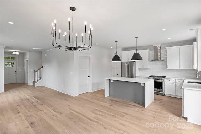 kitchen with high end appliances, a kitchen island, hanging light fixtures, light countertops, and wall chimney range hood