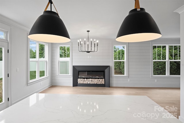 unfurnished living room featuring ornamental molding, a wealth of natural light, a fireplace, and light wood finished floors