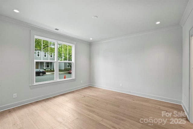 empty room with light wood-style floors, baseboards, visible vents, and crown molding