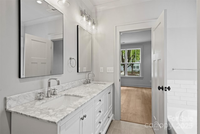 bathroom with double vanity, a bath, a sink, and wood finished floors