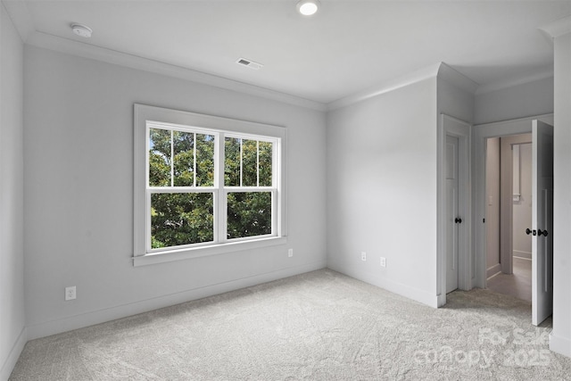 empty room featuring ornamental molding, light colored carpet, visible vents, and baseboards