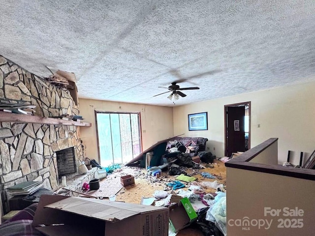 living room with ceiling fan, a fireplace, and a textured ceiling