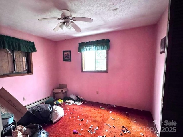 interior space with carpet floors, a baseboard radiator, a textured ceiling, and a ceiling fan