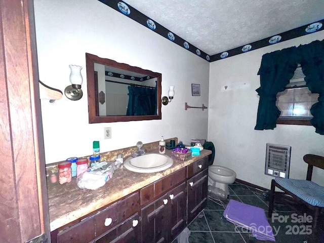 full bathroom with heating unit, toilet, vanity, a textured ceiling, and tile patterned floors