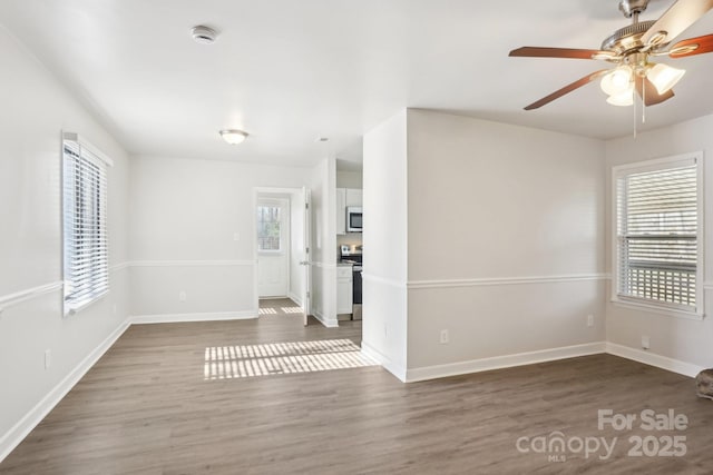 empty room featuring dark wood-style floors, baseboards, and a ceiling fan