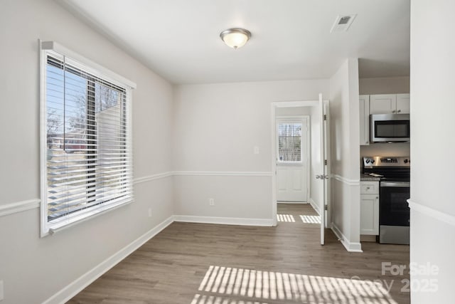 unfurnished dining area featuring visible vents, baseboards, and wood finished floors