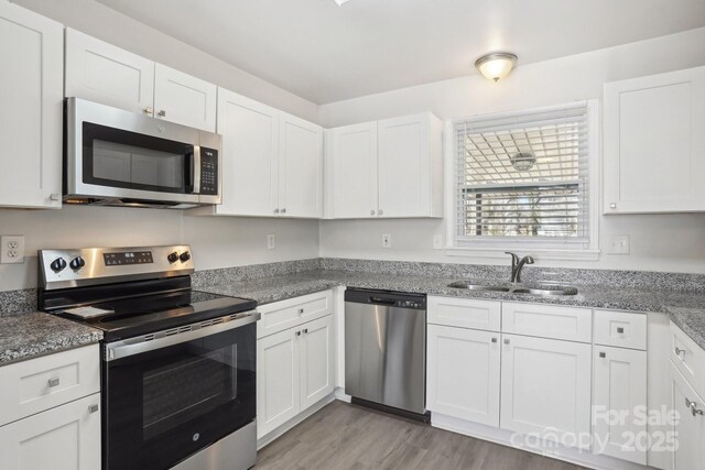 kitchen with light wood-style floors, white cabinetry, appliances with stainless steel finishes, and a sink