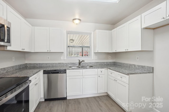 kitchen featuring appliances with stainless steel finishes, white cabinets, and a sink