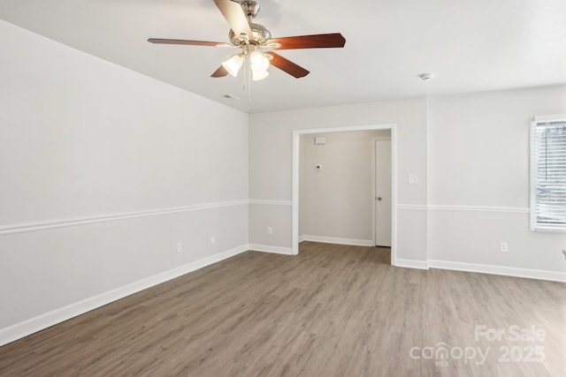 unfurnished room with wood finished floors, a ceiling fan, and baseboards