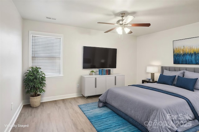 bedroom featuring baseboards, a ceiling fan, visible vents, and light wood-style floors