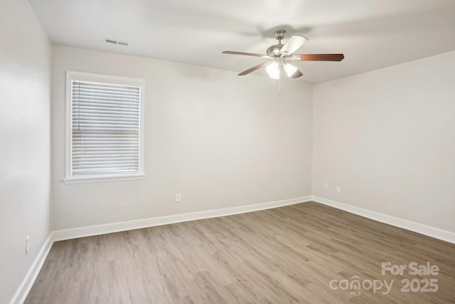 empty room with visible vents, baseboards, and wood finished floors