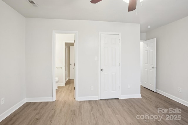 unfurnished bedroom with baseboards, visible vents, ceiling fan, wood finished floors, and ensuite bathroom