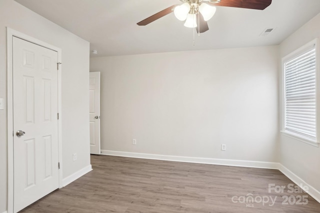 unfurnished room with visible vents, plenty of natural light, baseboards, and wood finished floors