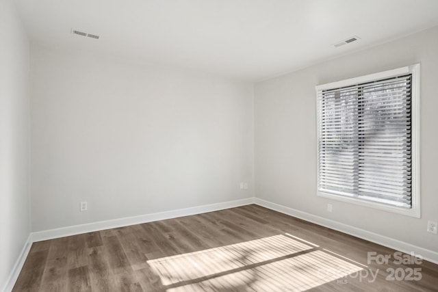 unfurnished room featuring visible vents, baseboards, and wood finished floors