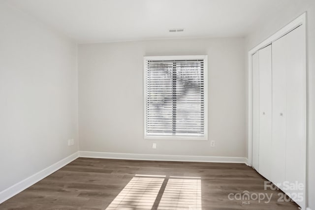 unfurnished bedroom with wood finished floors, visible vents, and baseboards