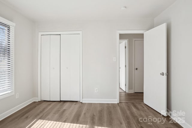 unfurnished bedroom featuring multiple windows, baseboards, and wood finished floors