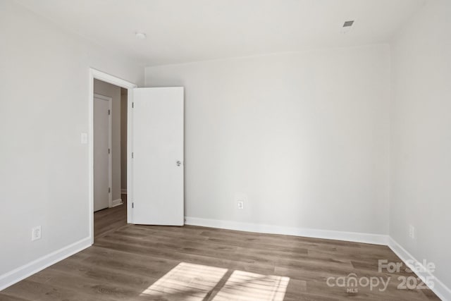 spare room with baseboards and wood finished floors