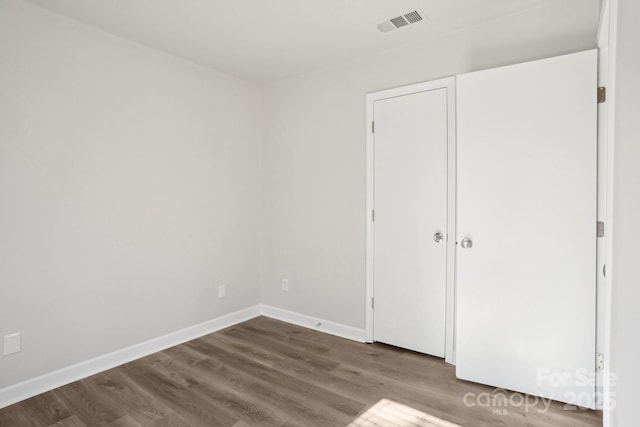 unfurnished bedroom featuring visible vents, dark wood finished floors, and baseboards