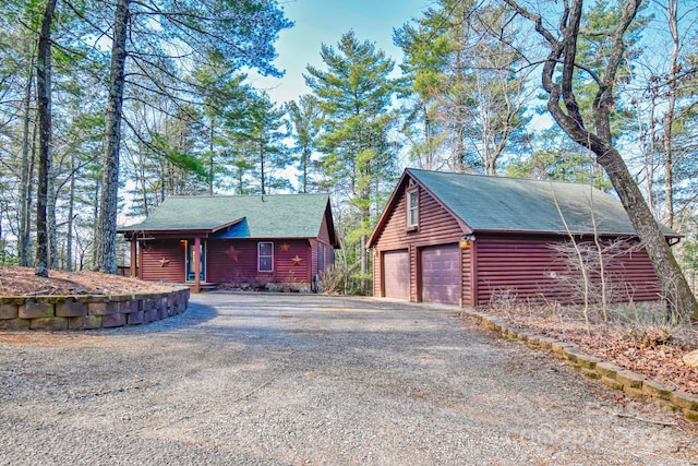 view of front of property with a garage, a shingled roof, and an outdoor structure