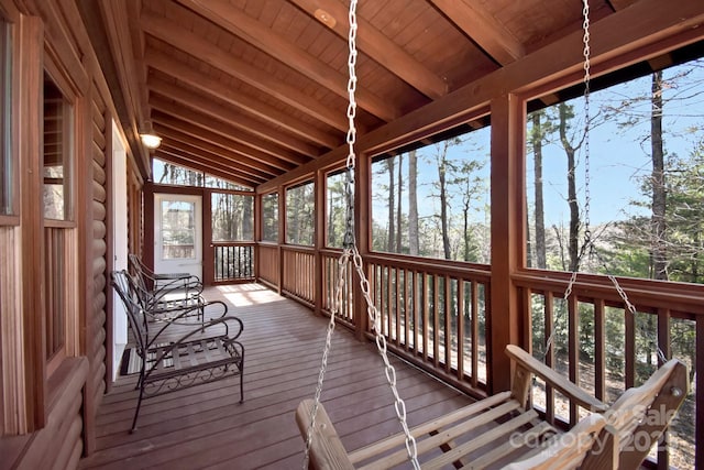 unfurnished sunroom featuring lofted ceiling with beams, wooden ceiling, and plenty of natural light