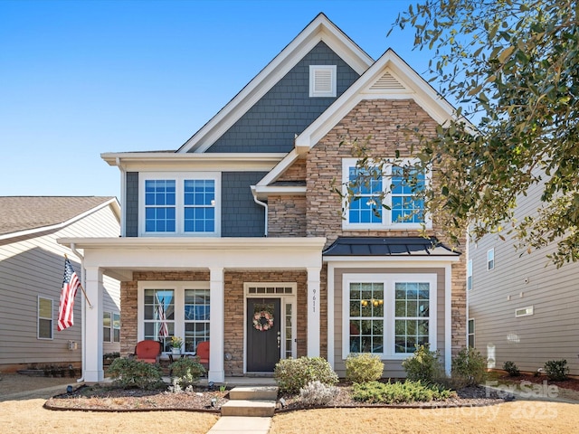 craftsman house with stone siding, covered porch, metal roof, and a standing seam roof