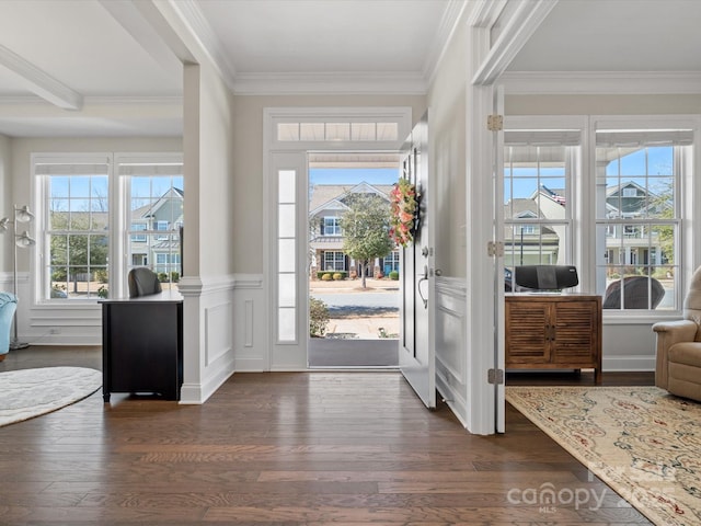 foyer entrance featuring dark wood-type flooring, a wainscoted wall, crown molding, and a decorative wall