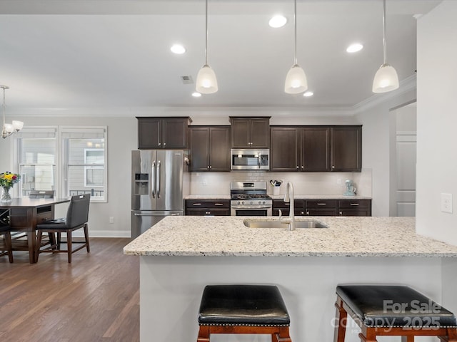 kitchen featuring dark brown cabinetry, decorative backsplash, appliances with stainless steel finishes, ornamental molding, and a sink