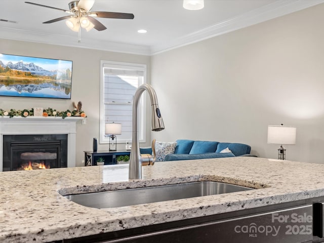 kitchen featuring ornamental molding, a glass covered fireplace, open floor plan, and a sink