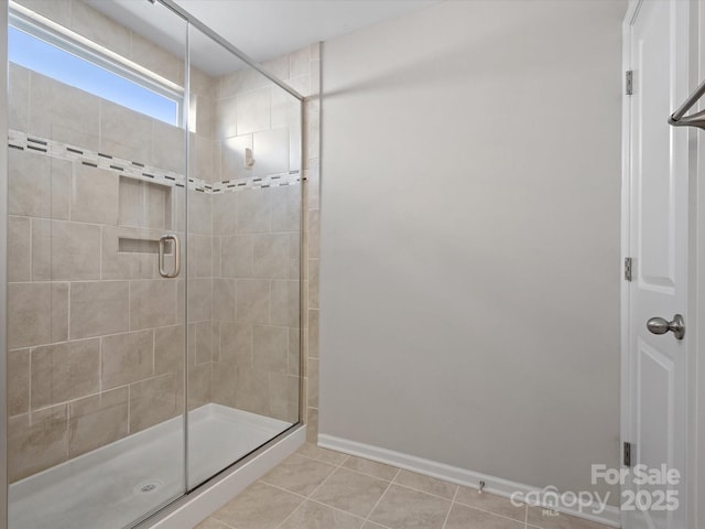 bathroom with a shower stall, baseboards, and tile patterned floors