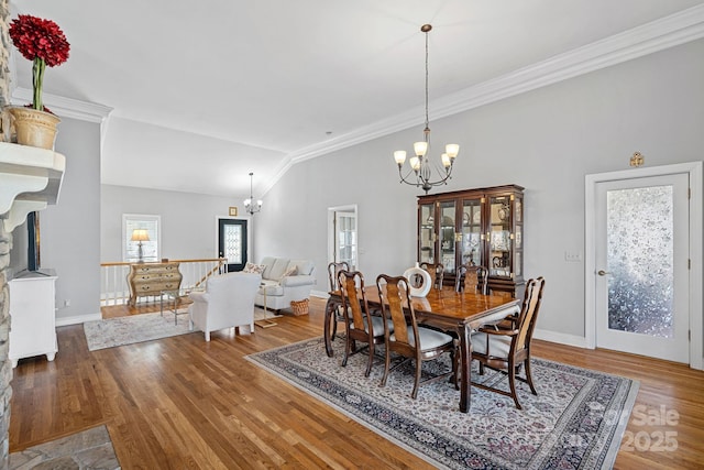 dining room featuring crown molding, wood finished floors, vaulted ceiling, and an inviting chandelier