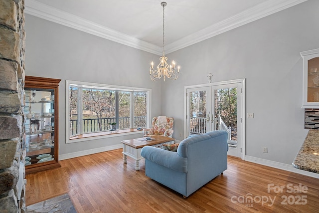 sitting room featuring light wood finished floors, baseboards, ornamental molding, and a notable chandelier