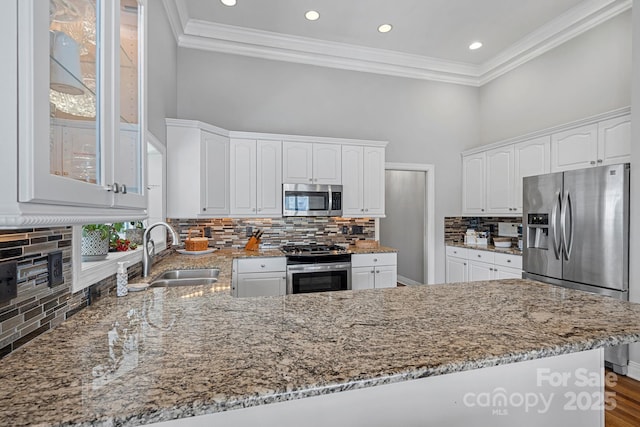 kitchen with stainless steel appliances, light stone counters, a sink, and white cabinets