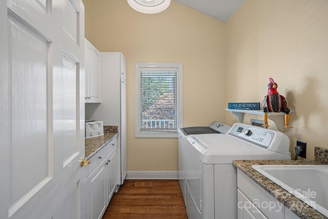 clothes washing area with cabinet space, baseboards, dark wood-style flooring, washing machine and dryer, and a sink