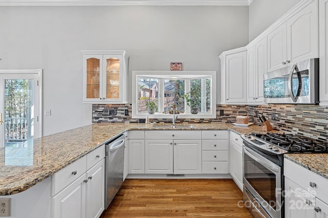 kitchen featuring white cabinetry, glass insert cabinets, stainless steel appliances, and a sink