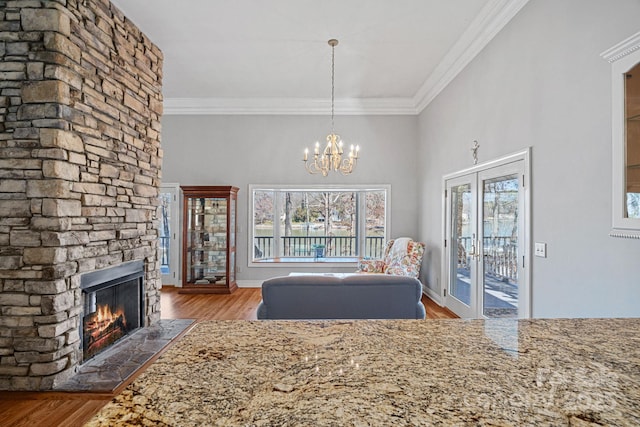 unfurnished living room with a notable chandelier, a fireplace, french doors, ornamental molding, and dark wood-style floors