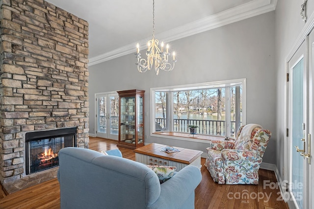 living room featuring dark wood-style floors, a stone fireplace, baseboards, and crown molding