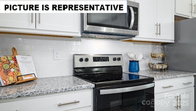 kitchen featuring appliances with stainless steel finishes, white cabinetry, backsplash, and light stone counters