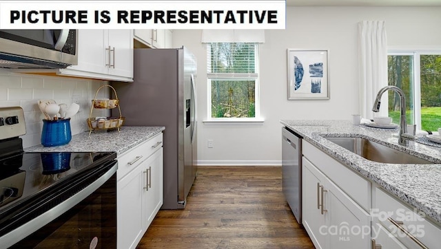 kitchen with appliances with stainless steel finishes, a sink, white cabinets, and decorative backsplash