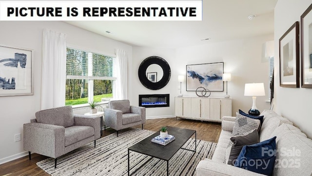 living room featuring a glass covered fireplace, dark wood finished floors, and baseboards