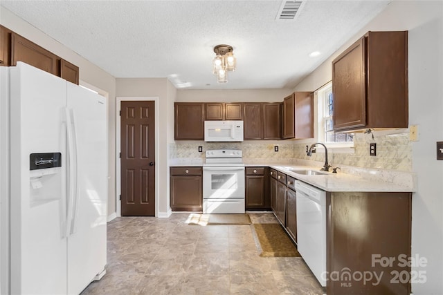 kitchen with visible vents, light countertops, backsplash, a sink, and white appliances