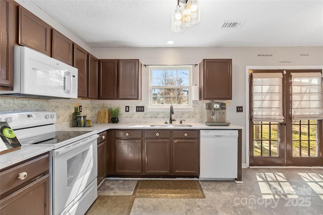 kitchen with light countertops, visible vents, backsplash, a sink, and white appliances