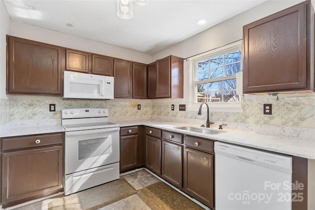 kitchen featuring a textured ceiling, white appliances, a sink, light countertops, and decorative backsplash