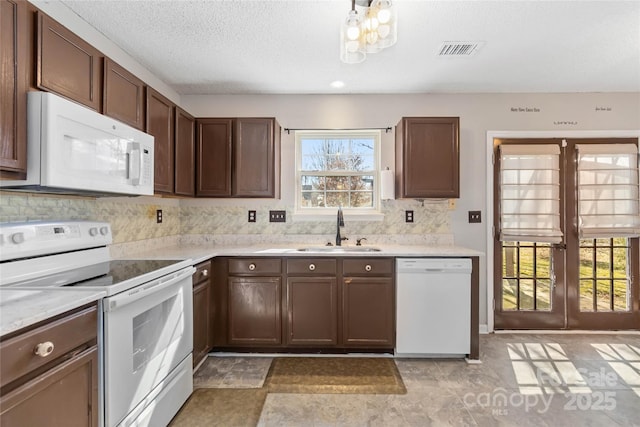 kitchen with light countertops, white appliances, visible vents, and a sink