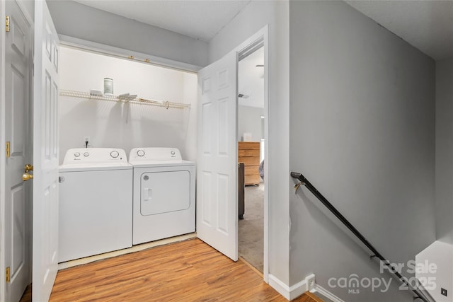 clothes washing area with laundry area, light wood finished floors, and separate washer and dryer