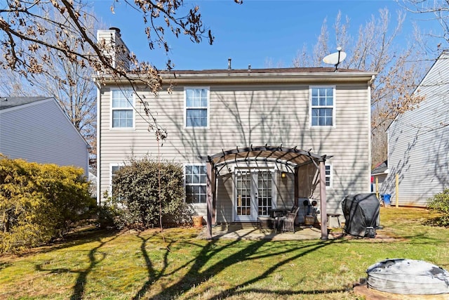 rear view of property featuring a yard, a chimney, a patio area, and a pergola